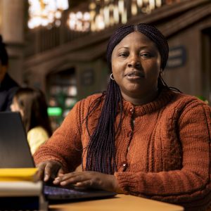 Portrait of african american librarian working with academic resources and learning materials within the public library database. Smiling woman focused on her educational profession.